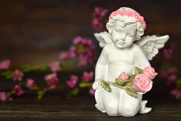 Φύλακας άγγελος και ανοιξιάτικα λουλούδια σε ξύλινο φόντο   - Φωτογραφία, εικόνα