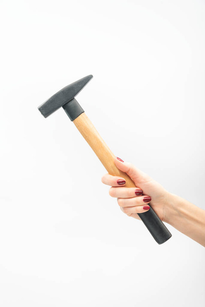 Female hand with red manicure holds hammer. On white background - Foto, immagini