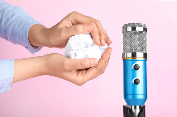 Woman making ASMR sounds with microphone and crumpled paper on pink background, closeup - 写真・画像