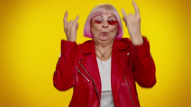 Overjoyed delighted crazy elderly woman showing rock n roll gesture by hands, cool sign, dancing - Footage, Video