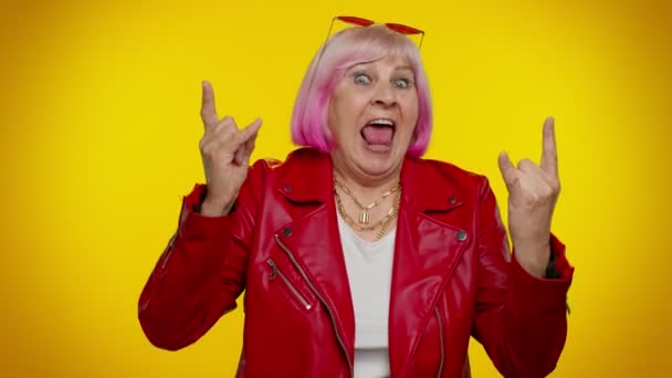 Overjoyed delighted crazy elderly woman showing rock n roll gesture by hands, cool sign, dancing - Footage, Video