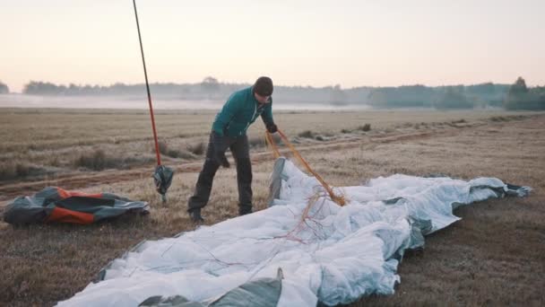 Mann packt Fallschirm aus, sucht Seilverbindung - Filmmaterial, Video