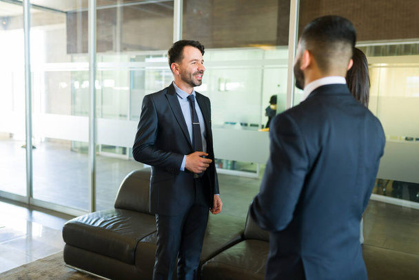 Szczęśliwy biznesmen w garniturze uśmiecha się i rozmawia z kolegami z pracy o udanych interesach  - Zdjęcie, obraz