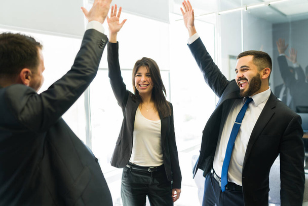 We did it! Attractive co-workers shouting because of their great success in the business company and raising their hands - Foto, imagen