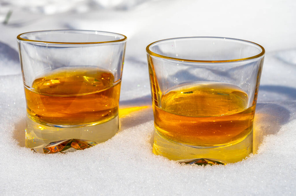 Soğuk skoç bardakları, beyaz kar üzerinde tek malt viski. - Fotoğraf, Görsel