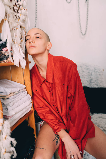 Woman wearing red shirt sitting and leaning against the wardrobe at home - Фото, изображение