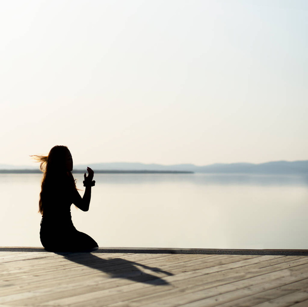 Silhouette ülő fiatal nő öntsön árnyékot fa móló nagy tó  - Fotó, kép