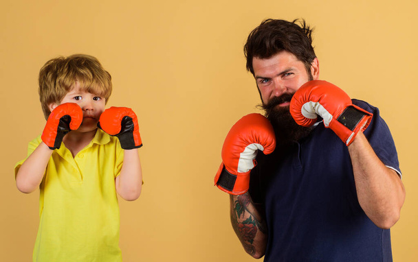 Child sportsman at boxing training with coach. Ready for sparring. Bearded sports man coaching boxing little boy. - Fotó, kép