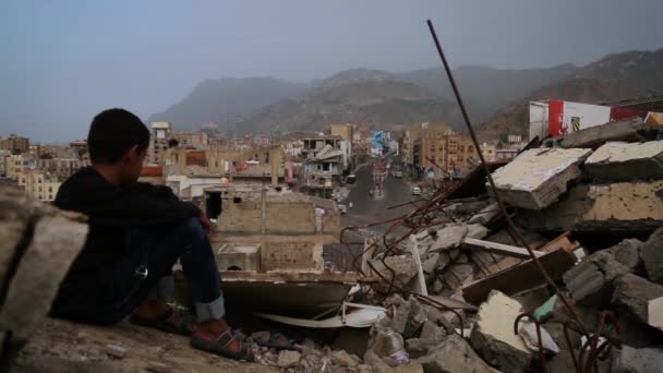   Taiz Jemen - 22 Sie 2016: Dziecko z Taiz City siedzi na ruinach zrujnowanego domu z powodu wojny z miastem-Jemenem. - Materiał filmowy, wideo
