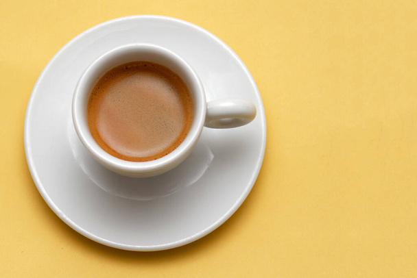 Traditional Italian espresso coffee in white cup on yellow background - Foto, imagen