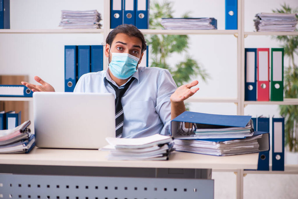 Jeune employé de sexe masculin travaillant au bureau pendant une pandémie - Photo, image