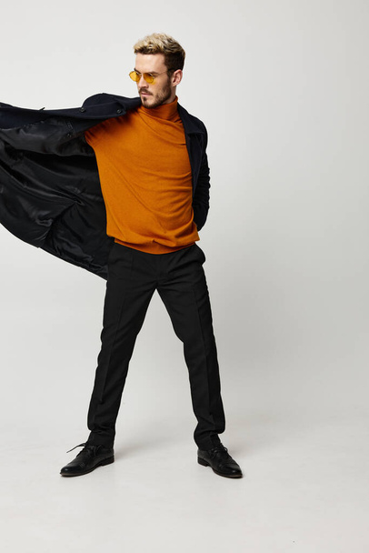 Açık ceketli enerjik bir adam ve turuncu kazaklı siyah pantolon mankeni. - Fotoğraf, Görsel