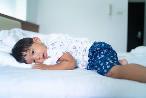 Little boy sleep on bed in morning wake up white blanket - 写真・画像