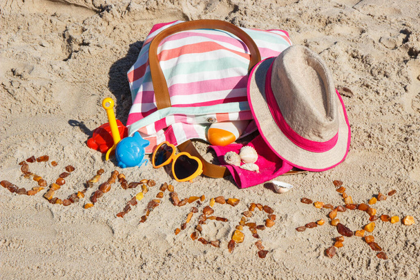 Inscription summer with shape of sun, accessories for sunbathing and children toys for playing on sand at beach. Travel, tourism and vacation time concept - Photo, image