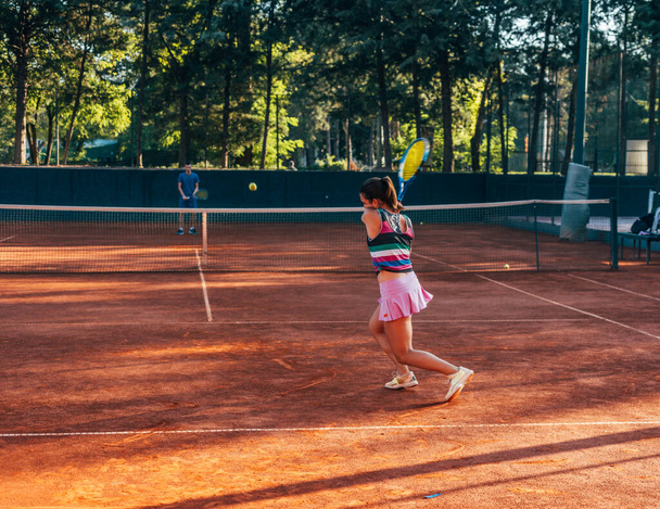 Vue de l'arrière d'une jeune femme payant le tennis sur un court à l'extérieur - Photo, image