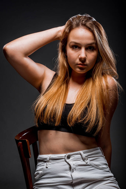Stylish fashion girl posing in trendy clothes against dark background - Фото, изображение