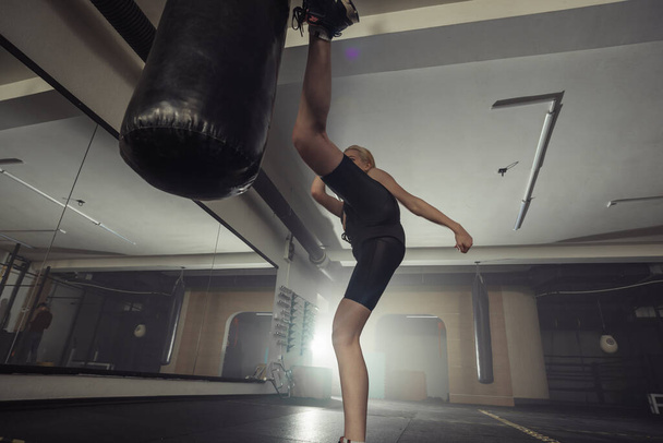 Joven adulto sexy mujer haciendo espalda pierna alta patada durante kickboxing. - Foto, imagen