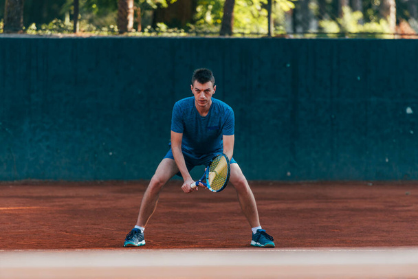 Profesyonel bir tenis maçında topu almayı bekleyen odaklanmış erkek sporcu. - Fotoğraf, Görsel
