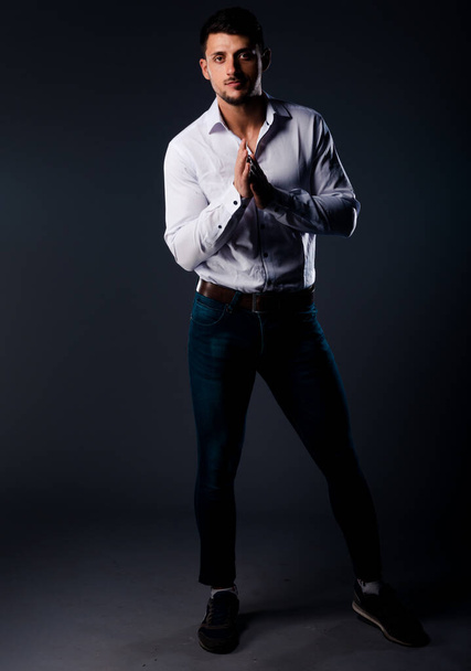 Portrait of a trendy guy wearing white shirt and blue denim pants - Foto, Imagem