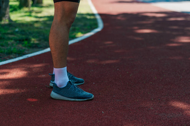 Photo rapprochée de chaussures de course masculines sur une piste de course dans le parc - Photo, image
