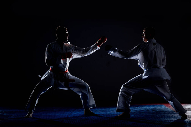 Ein Sportler mit schwarzem Gürtel und in Karategi führt eine formale Karate-Übung durch - Foto, Bild
