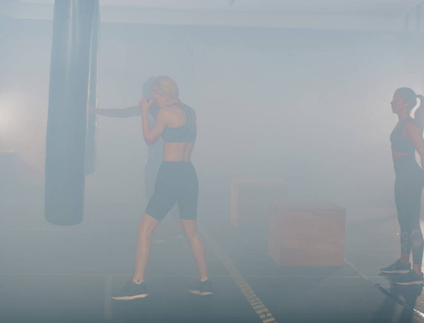 Portrait latéral d'une jeune femme faisant de la boxe avec de la fumée blanche en arrière-plan - Photo, image