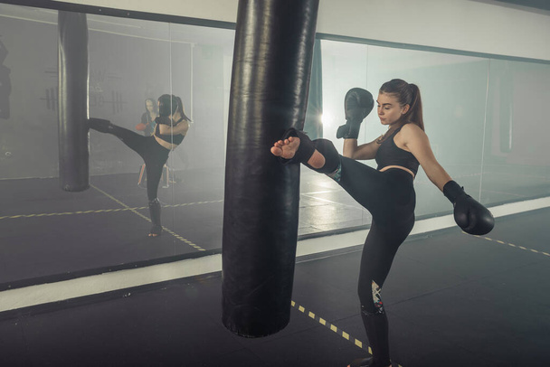 jong volwassen sexy vrouw doen back leg hoog kick tijdens kickboxing. - Foto, afbeelding