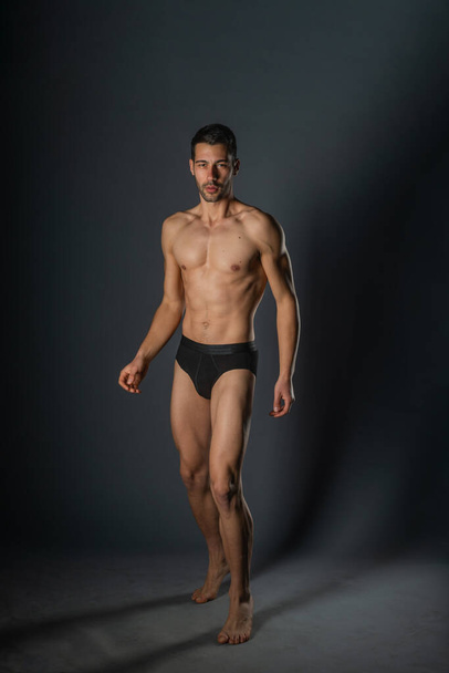 Sexy man with a muscular body posing naked with black underpants inside a studio - Zdjęcie, obraz