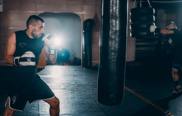 combattant beau musclé donnant un coup de pied avant fort lors d'un tour d'entraînement avec un sac de boxe
 - Photo, image