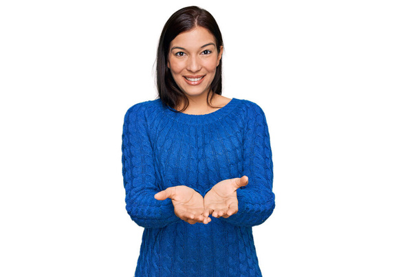 Mulher hispânica jovem vestindo roupas casuais sorrindo com as mãos palmas juntas recebendo ou dando gesto. segurar e proteger  - Foto, Imagem