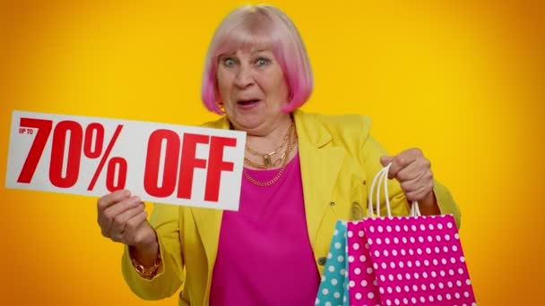 Seniorin zeigt Einkaufstüten und bis zu 70 Prozent Rabatt auf Aufschriften, Black Friday - Filmmaterial, Video