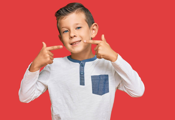 Adorable caucasian kid wearing casual clothes smiling cheerful showing and pointing with fingers teeth and mouth. dental health concept.  - Foto, afbeelding