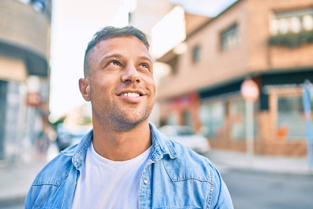 Genç beyaz adam gülümseyerek şehirde mutlu mesut yürüyor.. - Fotoğraf, Görsel
