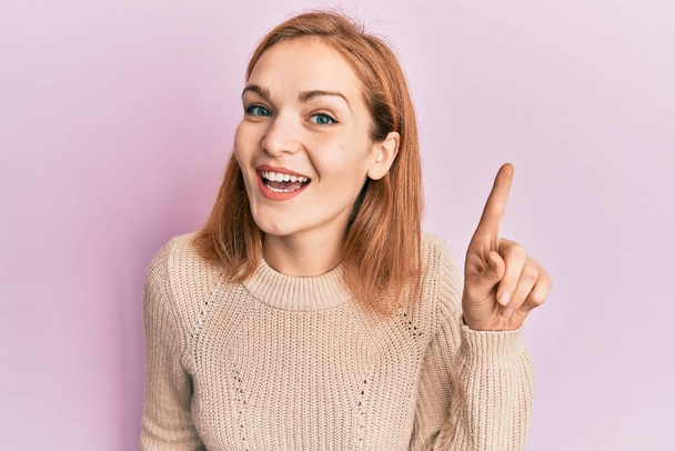 Young caucasian woman wearing casual clothes smiling with an idea or question pointing finger up with happy face, number one  - Photo, Image
