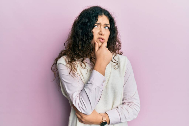 Young brunette woman with curly hair wearing casual clothes thinking worried about a question, concerned and nervous with hand on chin  - Photo, Image
