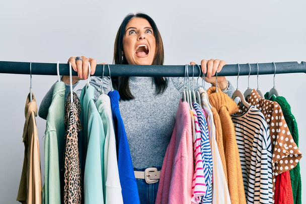 Middle age brunette woman working as professional personal shopper angry and mad screaming frustrated and furious, shouting with anger looking up.  - Foto, Bild