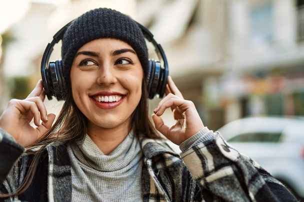 Young hispanic woman smiling happy using headphones at the city. - Fotoğraf, Görsel