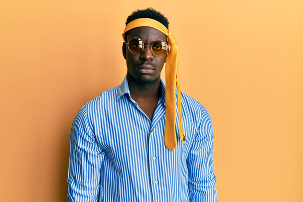 Handsome black man drunk wearing tie over head and sunglasses relaxed with serious expression on face. simple and natural looking at the camera.  - Foto, afbeelding