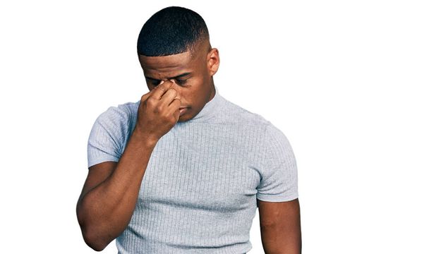 Молодий чорний чоловік у повсякденній сорочці втомився натирати ніс і очі, відчуваючи втому і головний біль. концепція стресу та розчарування
.  - Фото, зображення