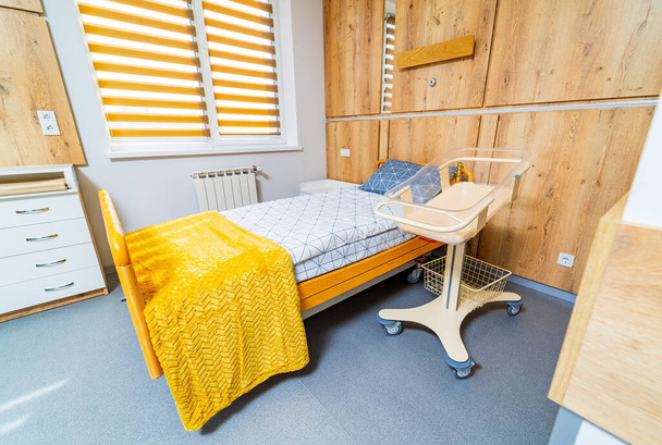 Bed for mother and newborn child cradle in modern hospital. Up-to-date interior in clinic. Ligth colors in clinic room. Closeup. - Photo, image