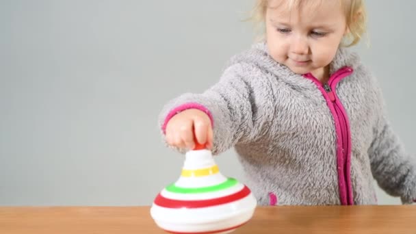 Ein Kind spielt mit einem Wirbel, ein kleines Mädchen wirbelt ein Spielzeug auf dem Tisch im Kinderzimmer. - Filmmaterial, Video