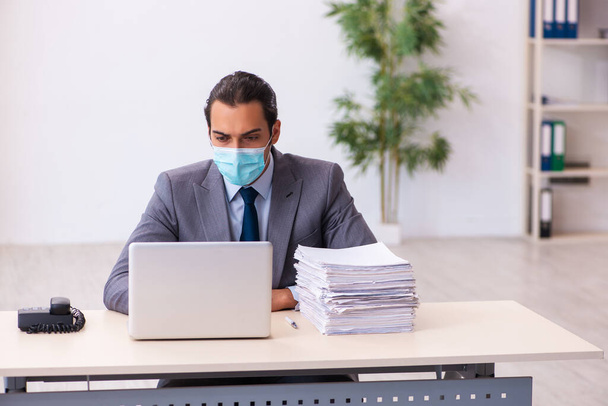 Joven empleado masculino usando máscara durante pandemia - Foto, Imagen