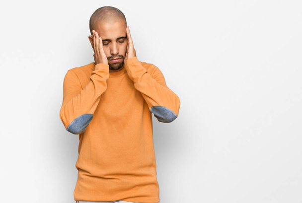 Hispánský dospělý muž v neformálním zimním svetru s rukou na hlavě kvůli bolesti hlavy, protože je ve stresu. trpící migréna.  - Fotografie, Obrázek
