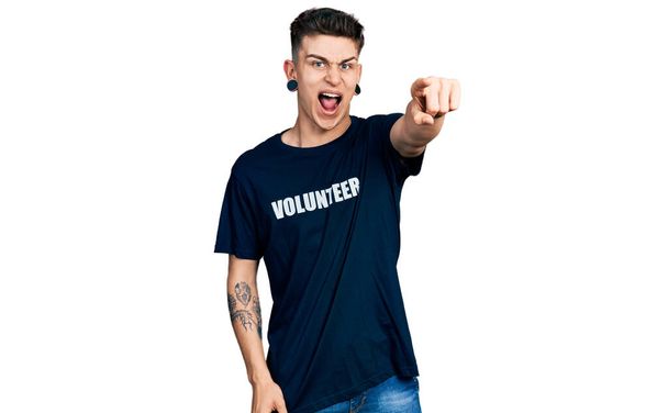 Молодий білий хлопчик з розширенням вух носить волонтерську сорочку, вказуючи на невдоволення і розчарування в камері, сердитий і лютий з вами
  - Фото, зображення