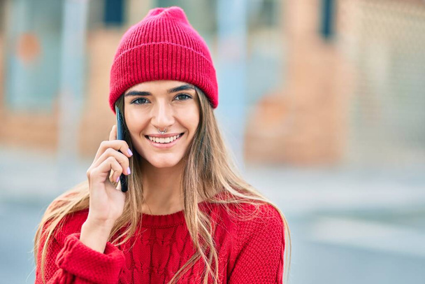 Kış tarzı giyinen genç İspanyol kadın şehirde akıllı telefondan konuşuyor.. - Fotoğraf, Görsel