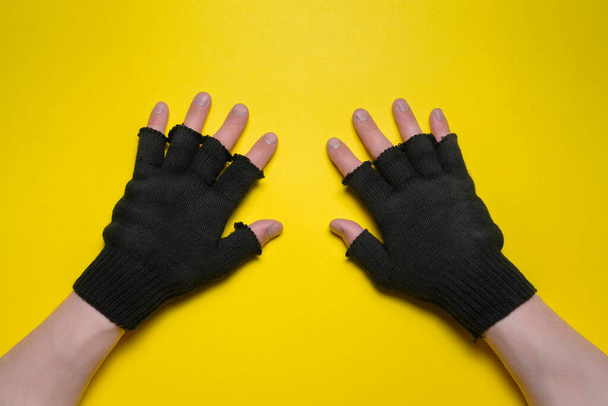 Male hands in black construction gloves on the yellow flat lay background. - Foto, imagen