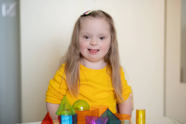 Egy gyönyörű lány Down-szindrómás játszik egy építész, fényes átlátszó számok, korai fejlődése fogyatékos gyermek. - Fotó, kép