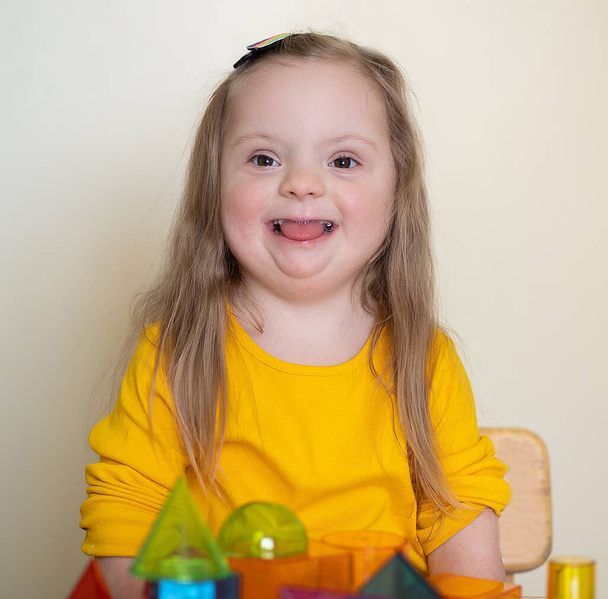 Krásná dívka s Downovým syndromem hraje s konstruktérem, jasné transparentní postavy, raný vývoj postiženého dítěte. - Fotografie, Obrázek
