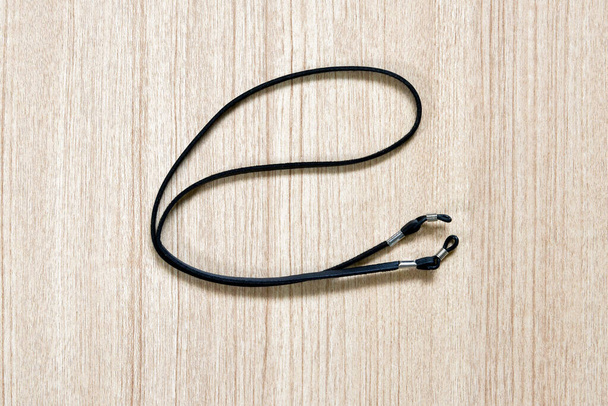 leather black eyeglasses strap on a wooden background - 写真・画像