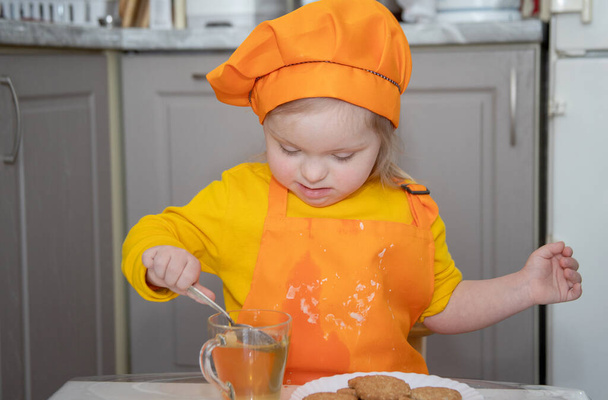 child with Down syndrome cooking, a portrait of a disabled girl. - Photo, Image
